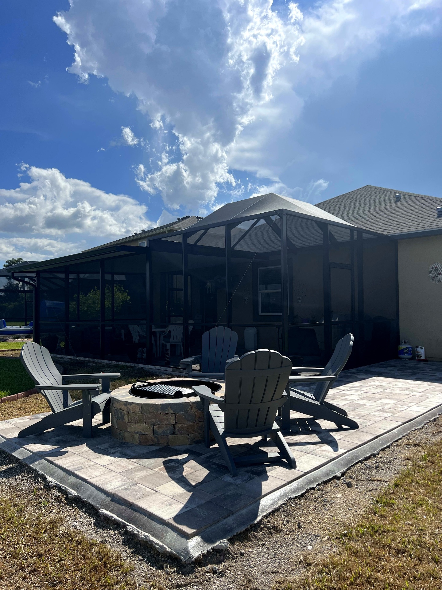 Paver patio with built-in fire pit and screen enclosure — Wesley Chapel, FL